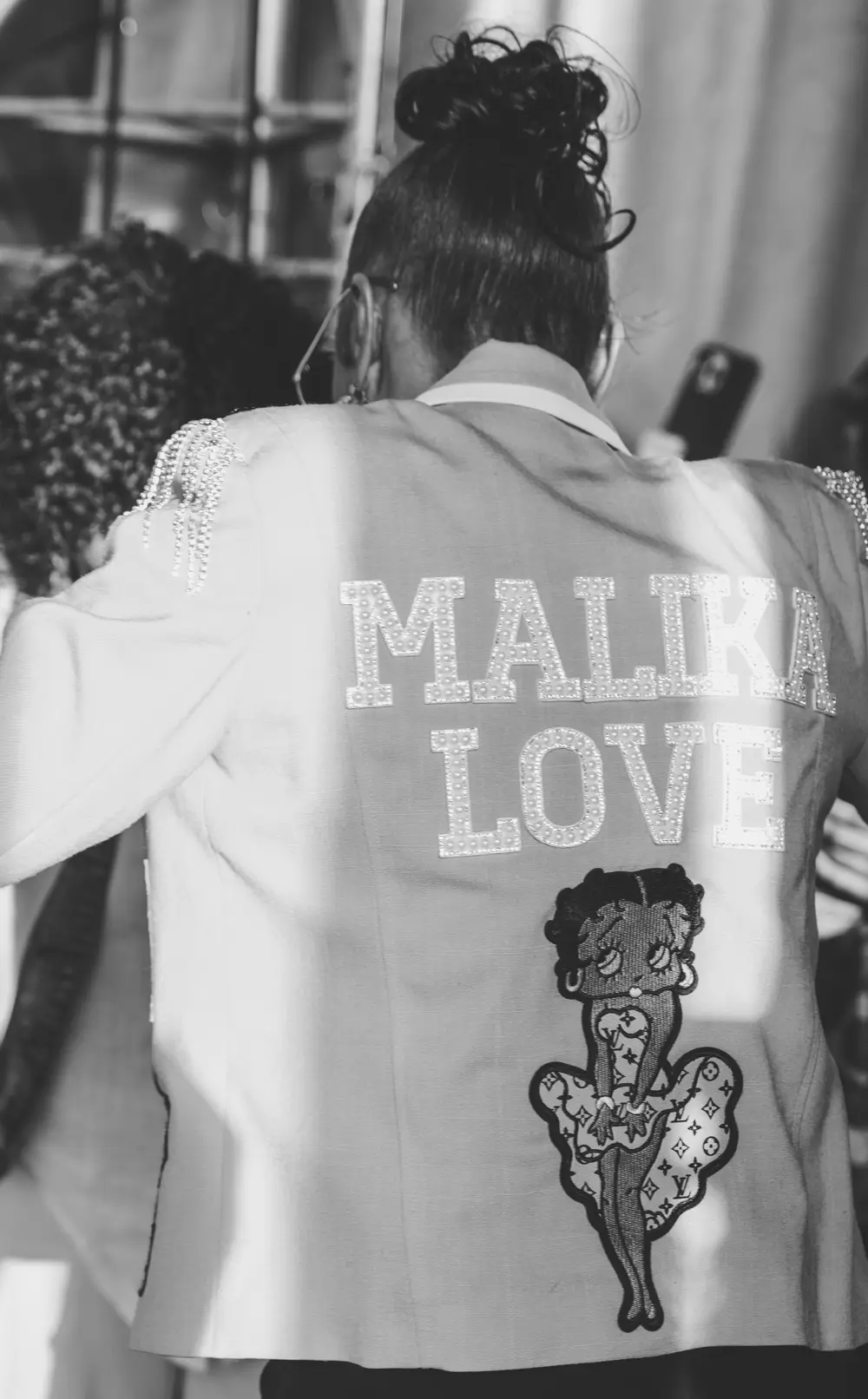 Malika Love seen from behind, her name across the back of her jacket