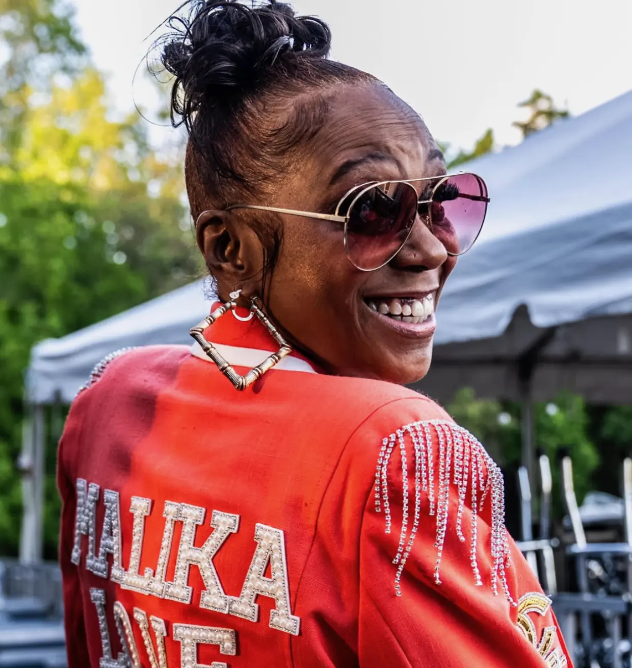 Malika Love, smiling over her shoulder in a red jacket with her name across the back
